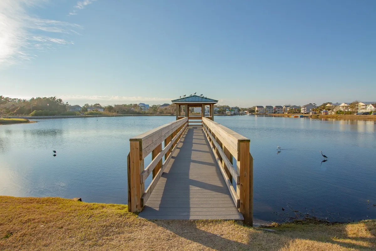 A tranquil scene featuring a gazebo and dock over calm water, surrounded by lush greenery—ideal for leisurely walks, peaceful moments by the water, and enjoying the outdoors with pets.